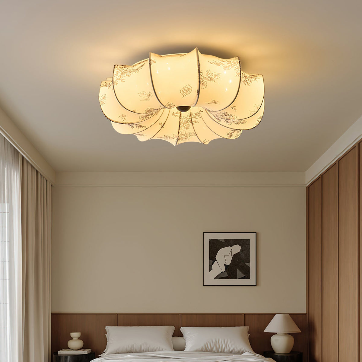 This Clérachic fabric ceiling light is lit above a bedroom with beige curtains and a framed black-and-white print.