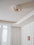 Clérachic ceiling light, unlit, seen from the corner of a white room, with the petal shape clear against the ceiling.