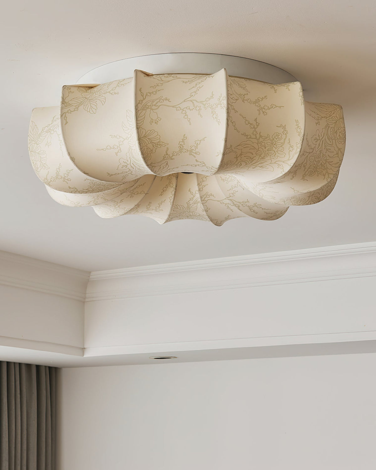 Close view from below of this unlit Clérachic ceiling light, with a pale floral pattern on its fabric petals.
