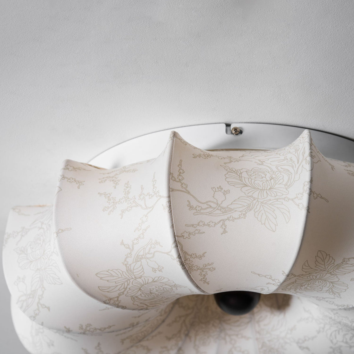 Close view of the folded fabric petals and dark wooden knob on this Clérachic ceiling light, with a faint branch print.