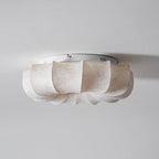 Side view of the white base plate and fabric petals on this Clérachic ceiling light, seen close to the ceiling.