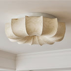 A Clérachic fabric ceiling light seen from below, unlit, with a coved ceiling edge in the corner of the frame.