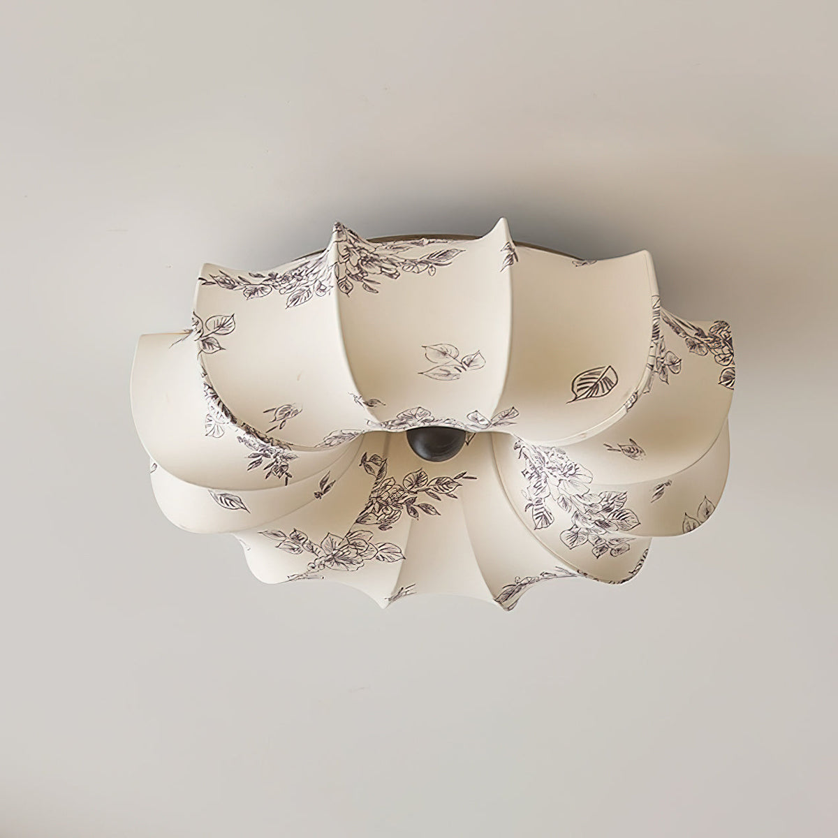 Clérachic ceiling light with a dark grey floral print on its beige fabric petals, seen from below against a pale ceiling.