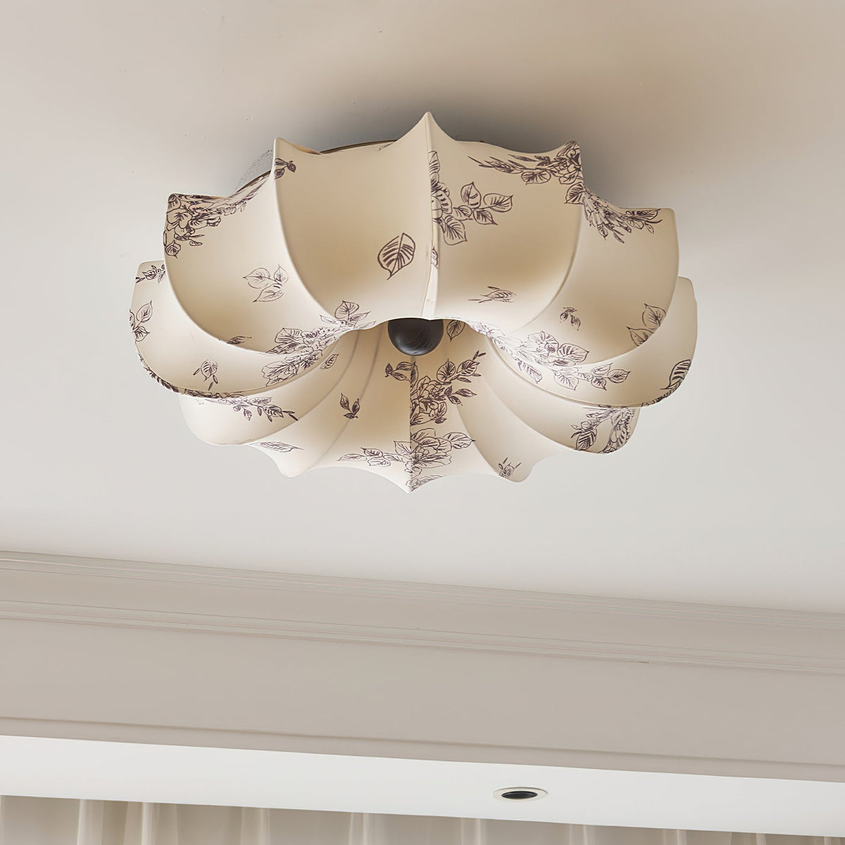 A Clérachic fabric ceiling light with a grey floral print on beige petals, unlit, seen above a coved ceiling edge.
