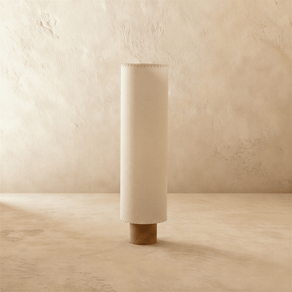 Clérachic floor lamp switched off, a tall beige fabric cylinder shade with hand-laced edges on a round wooden base.