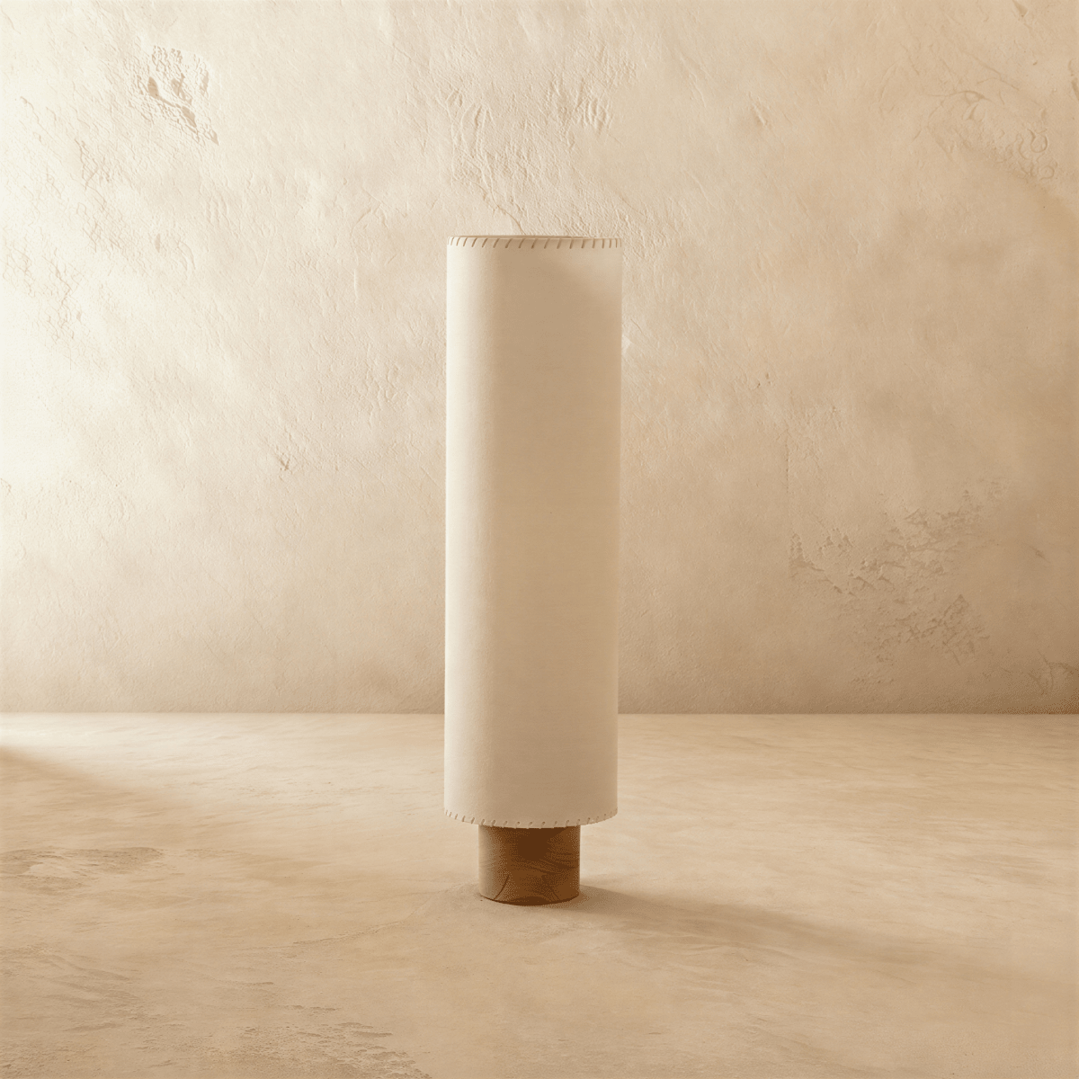 Clérachic floor lamp switched off, a tall beige fabric cylinder shade with hand-laced edges on a round wooden base.