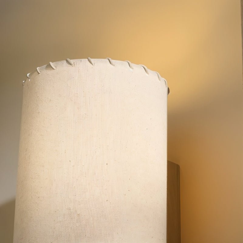 Close view of the Clérachic floor lamp shade top, textured beige fabric with a white laced edge, glowing warm.