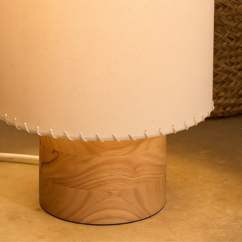 Close view of the Clérachic floor lamp base, a round light-wood cylinder under the laced beige shade, with a white cord.