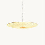 A shallow, gathered beige fabric disc hangs from a thin twisted cord, this Clérachic pendant light glowing on a plain white backdrop.