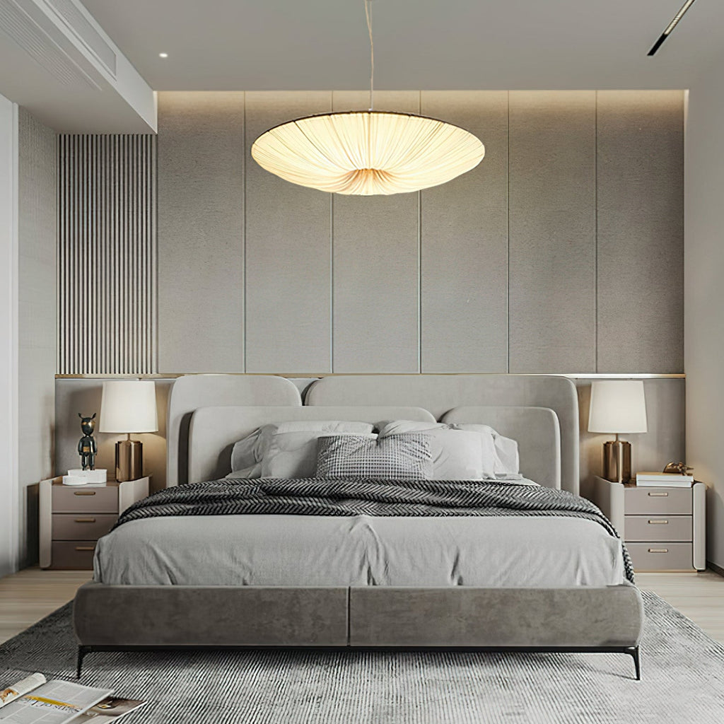 A shallow fabric pendant glows over a grey upholstered bed with matching bedside tables and lamps, a Clérachic bedroom scene.