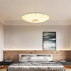 This Clérachic pendant glows over a bedroom with an oak-panelled headboard wall, a seascape print and soft strip lighting.