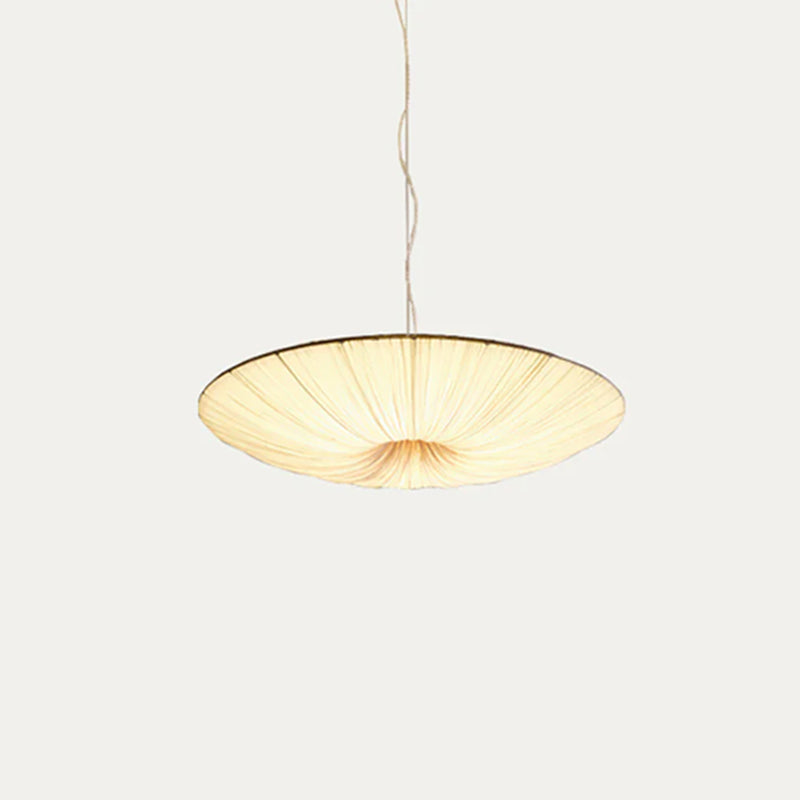 This Clérachic pendant light, a wide beige fabric disc on a twisted cord, viewed from the side on a pale grey backdrop.