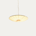 This Clérachic pendant light, a wide beige fabric disc on a twisted cord, viewed from the side on a pale grey backdrop.