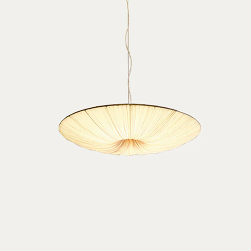 The beige fabric shade of this Clérachic pendant seen from slightly above its rim, its pleats glowing on a light grey backdrop.