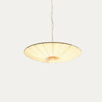 The beige fabric shade of this Clérachic pendant seen from slightly above its rim, its pleats glowing on a light grey backdrop.