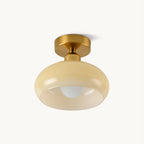 Beige glass dome with a gold-toned canopy and a visible round bulb, this Clérachic flush-mount ceiling light on a plain off-white backdrop.