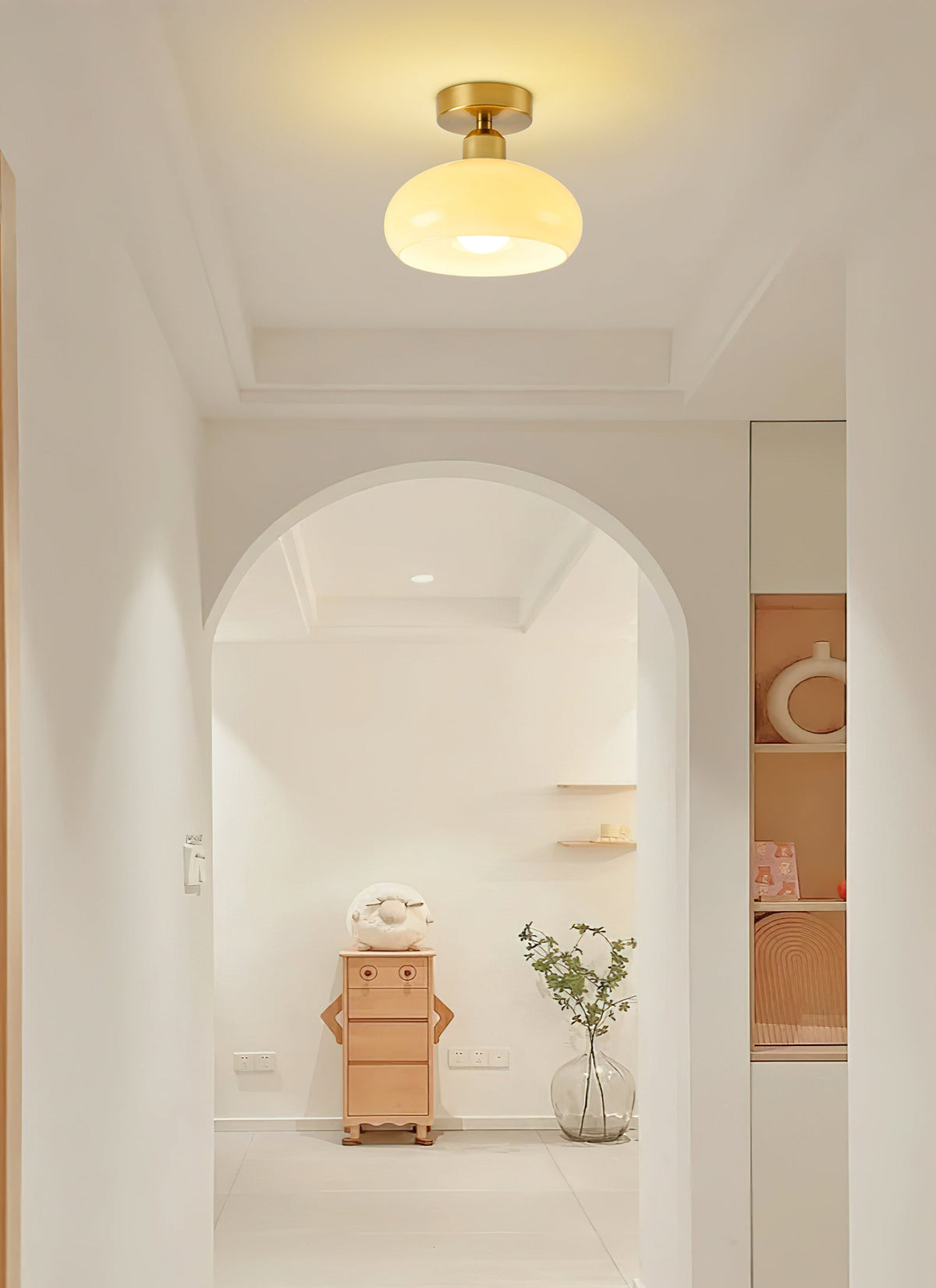 Warm-glowing Clérachic ceiling light with a brass canopy, set in a recessed ceiling above a cream arched doorway.