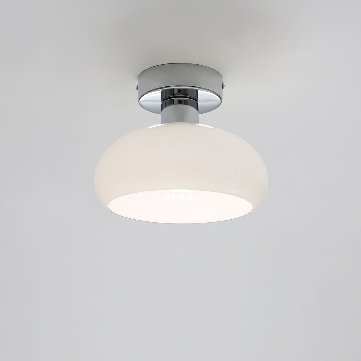 White glass dome with a chrome canopy and a bright inner rim, a Clérachic ceiling light on a pale grey backdrop.