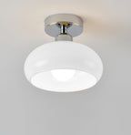 Chrome-canopied Clérachic ceiling light with a smooth white glass dome and a round bulb inside, on a light grey backdrop.