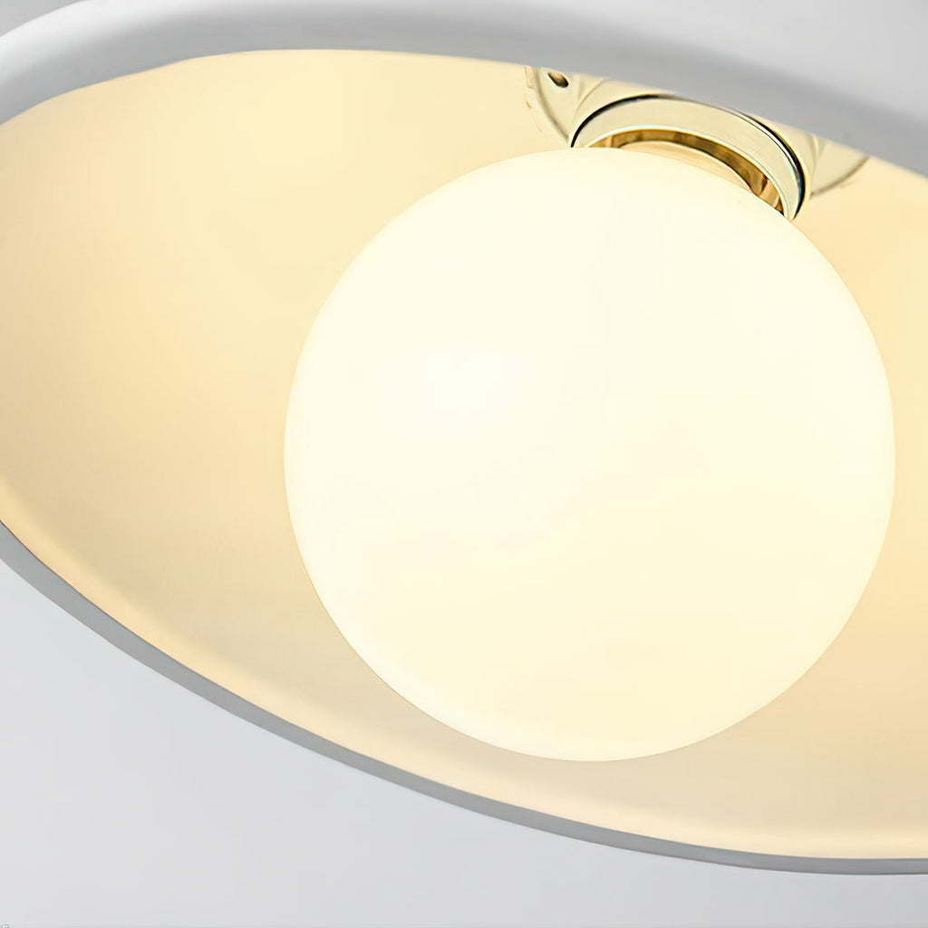 Looking up into the white inner rim of a Clérachic ceiling light, with the round bulb sitting in its brass holder.