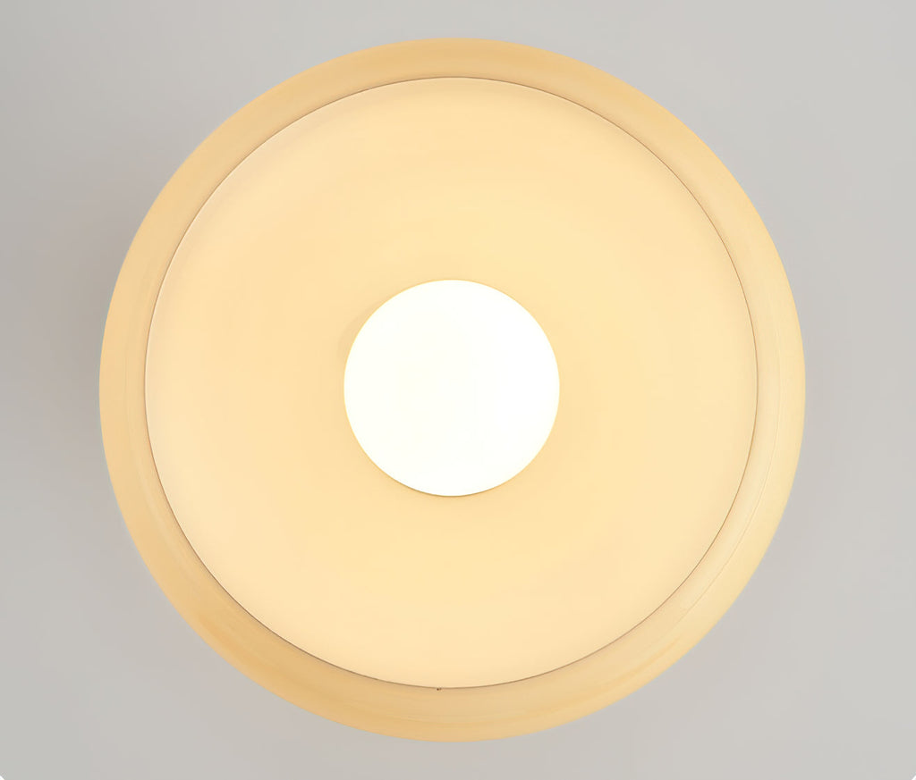 Underside view of the beige glass dome of this Clérachic ceiling light, the round bulb glowing at its centre.