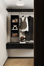 A Clérachic ceiling light with a white glass dome above a walk-in wardrobe with dark shelving and hanging coats.