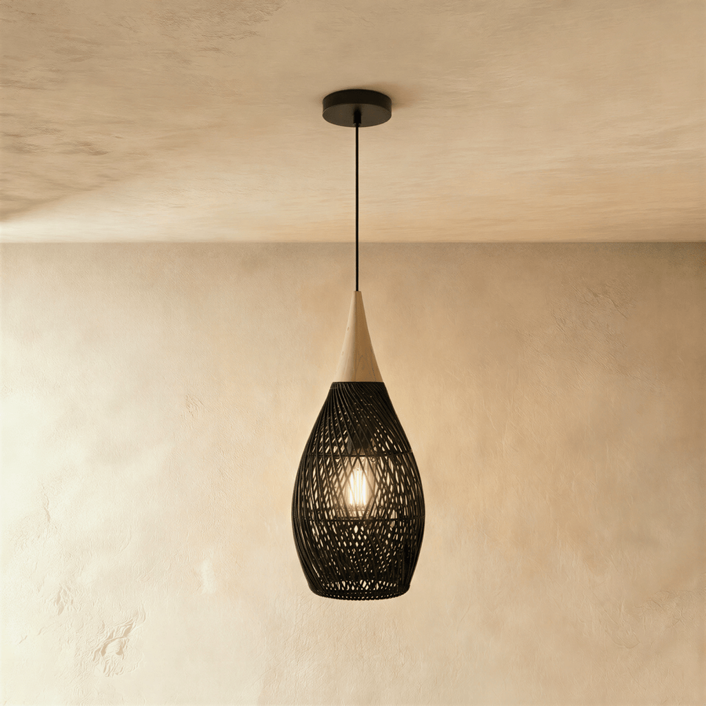 Clérachic black rattan pendant light with a woven teardrop shade and beige wood cap, viewed against a plaster wall.