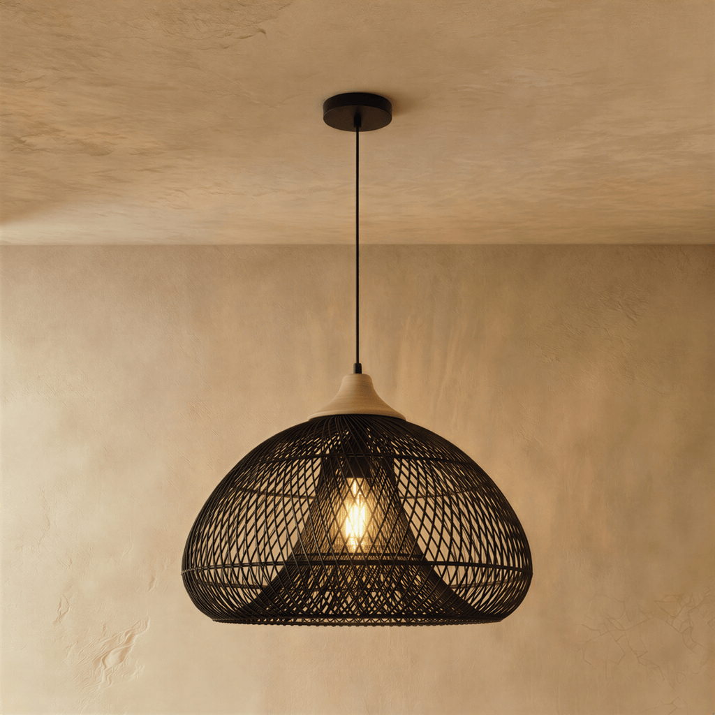 Clérachic black rattan pendant light in a wide woven dome shade with a beige wood cap against a plaster wall.