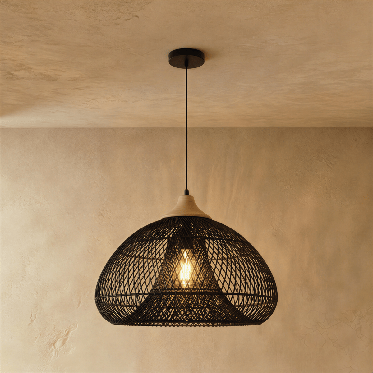 Clérachic black rattan pendant light in a wide woven dome shade with a beige wood cap against a plaster wall.