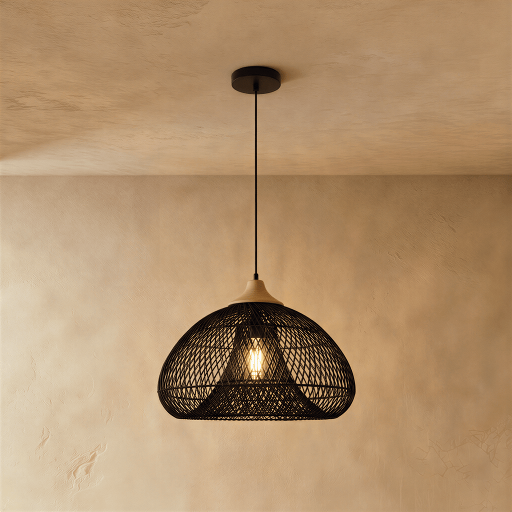 Clérachic black woven rattan dome pendant light with a beige wood cap, lit and hanging near a plaster wall.