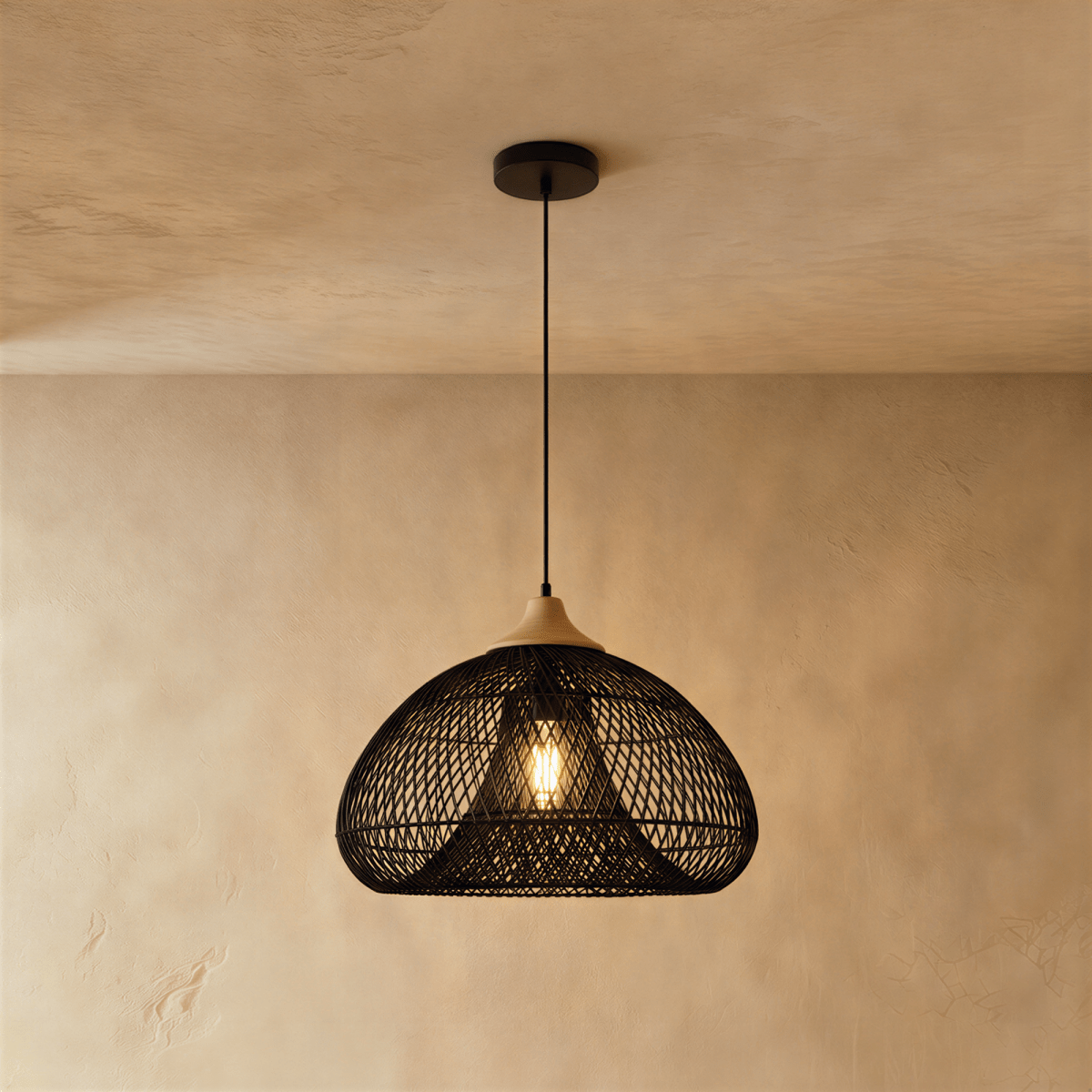Clérachic black woven rattan dome pendant light with a beige wood cap, lit and hanging near a plaster wall.