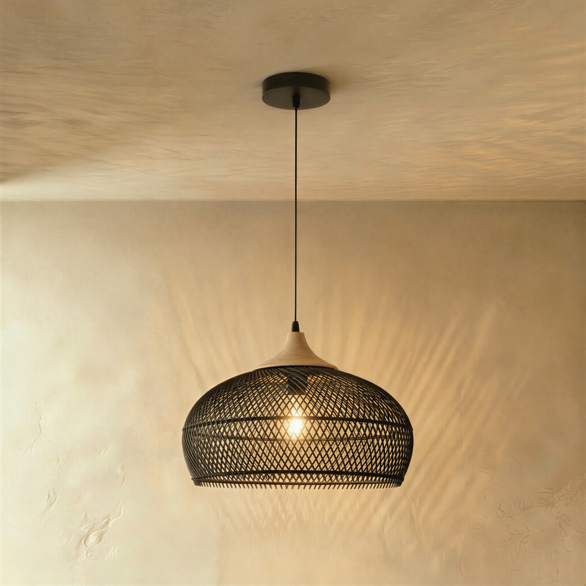 Clérachic black woven rattan pendant light with a rounded dome shade and beige wood cap, lit against plaster.