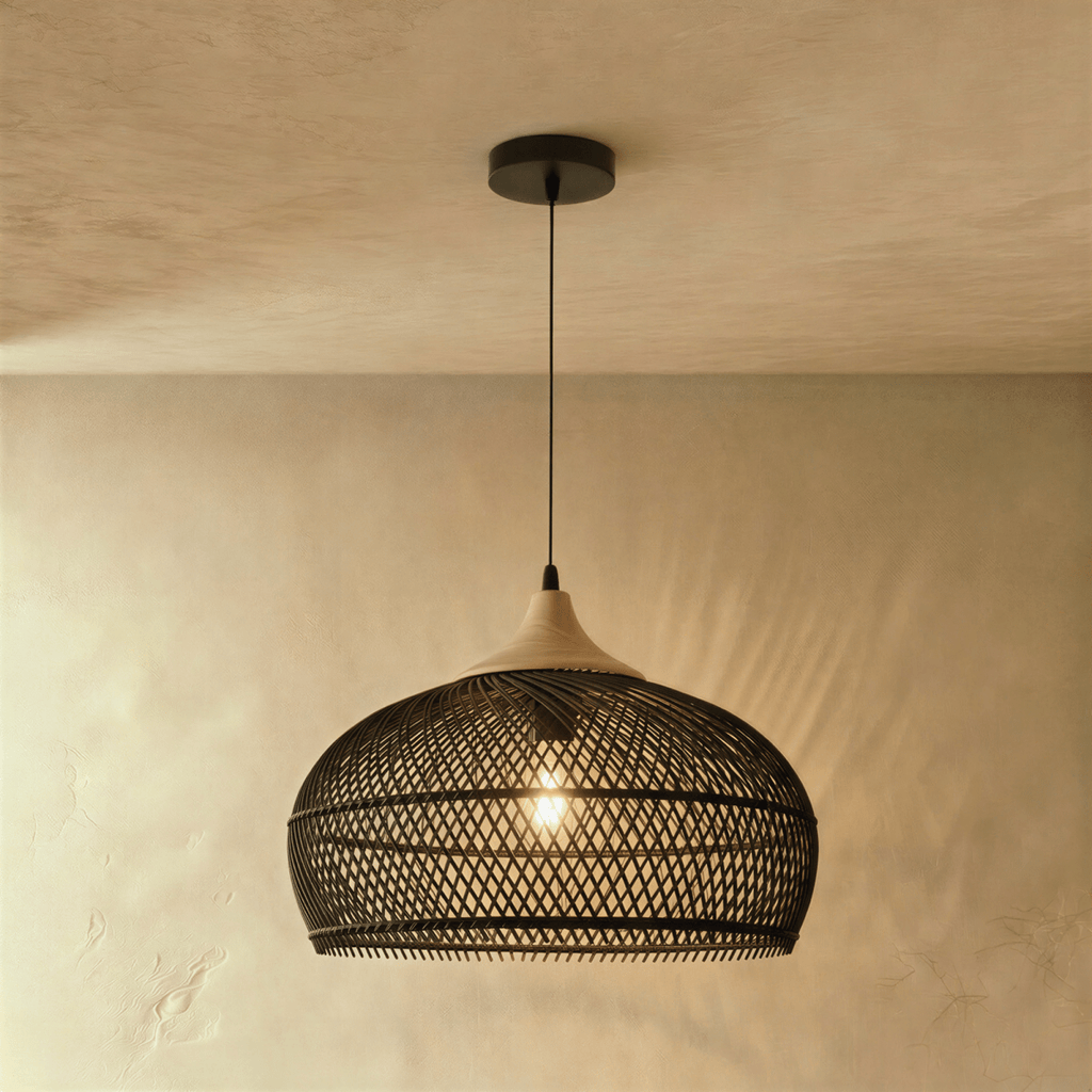 Clérachic black woven rattan pendant light with a dome shade and beige wood cap, glowing against a plaster wall.