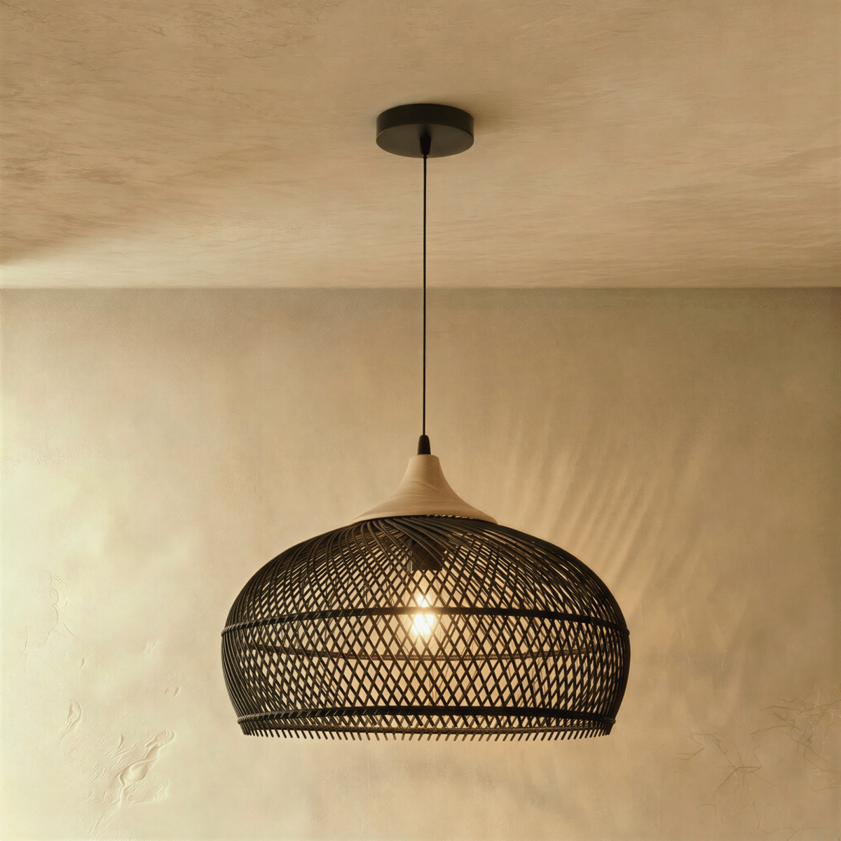 Clérachic black woven rattan pendant light with a dome shade and beige wood cap, glowing against a plaster wall.