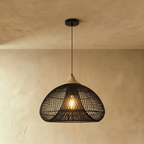 Clérachic black rattan pendant light with a woven dome shade and beige wood cap suspended over a plaster interior.