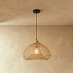 Clérachic natural rattan pendant light with a woven beige dome shade and wood cap glowing against a plaster wall.
