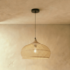 Clérachic natural rattan pendant light with a rounded beige dome shade and wood cap against a warm plaster wall.