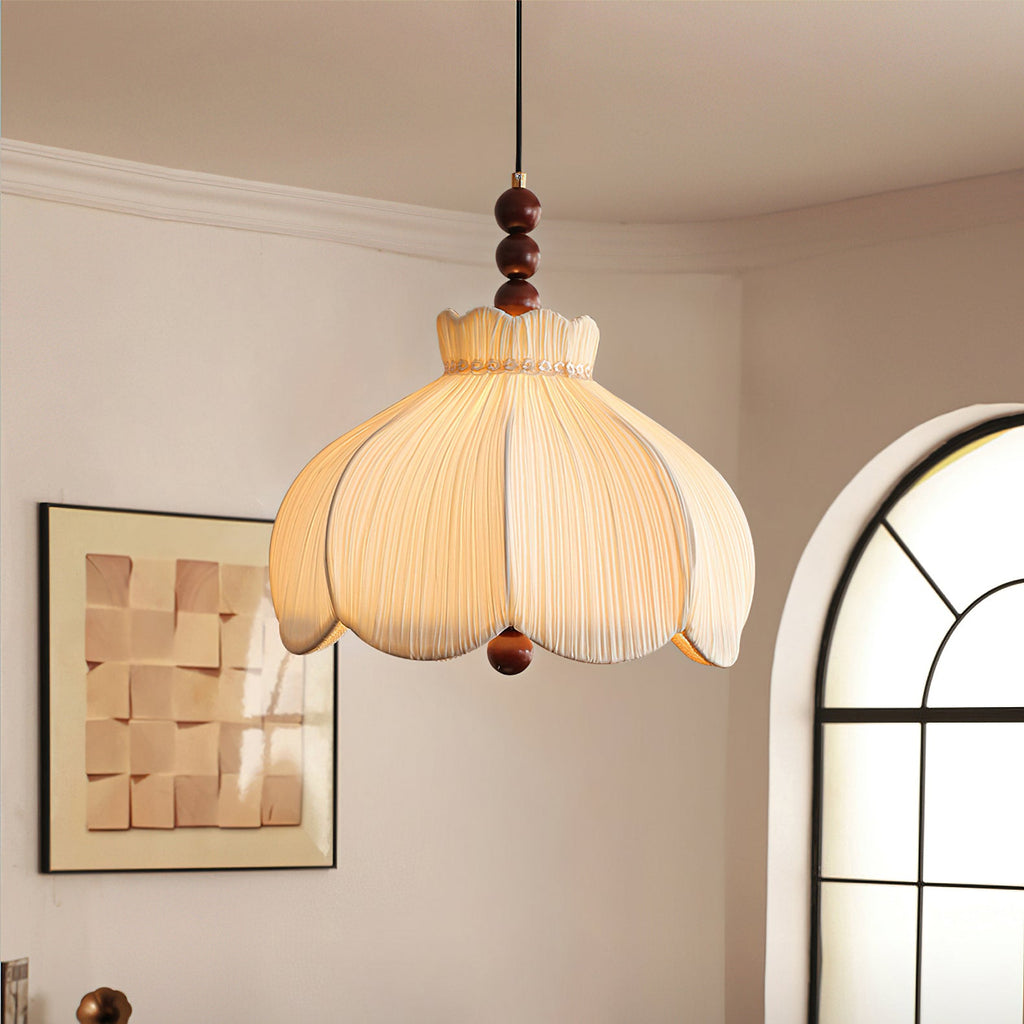 This Clérachic pleated pendant glows warm in a room with a framed tile artwork and an arched window.