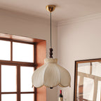 Clérachic petal-shaped pendant on a brass canopy and thin cord, hanging near a window and a framed mirror.
