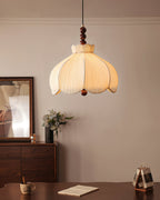 Smaller view of a lit Clérachic beige pendant in a dining corner, with a walnut sideboard and flowers behind.
