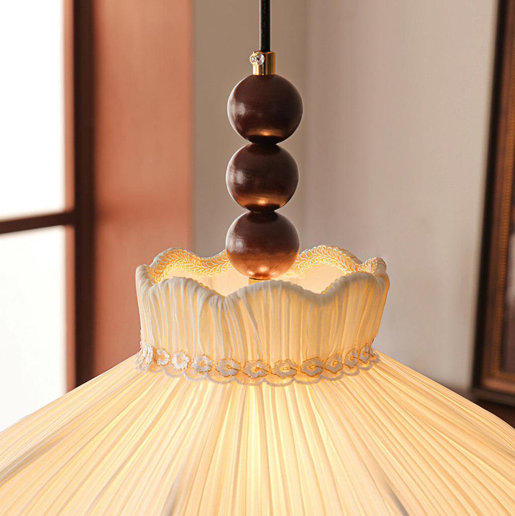 Close view of the three walnut-coloured beads and the lace-trimmed, ruffled collar on this Clérachic pendant.