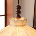 Close view of the three walnut-coloured beads and the lace-trimmed, ruffled collar on this Clérachic pendant.