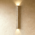 Clérachic slim square travertine wall light without a globe, casting soft light up and down a limewash wall.
