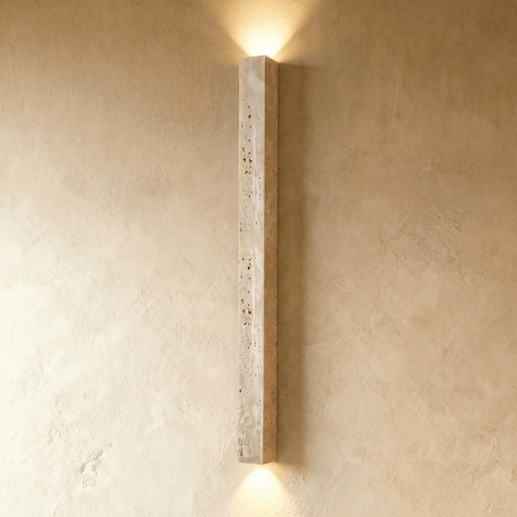 Clérachic floor-length travertine wall light without a globe, lit at both ends against a textured limewash wall.