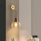 Clérachic bell sconce mounted on a textured concrete-look wall above a small potted plant in a hallway corner.