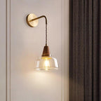 The Clérachic sconce lights a white paneled wall beside a charcoal herringbone curtain in a bedroom setting.