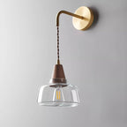 Clérachic bell glass sconce shown straight-on against plain gray, highlighting the brass ferrule and visible filament bulb.