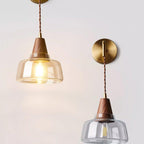 Two Clérachic bell glass sconces mounted side by side on a gray wall, one lit and one unlit, showing the pair together.