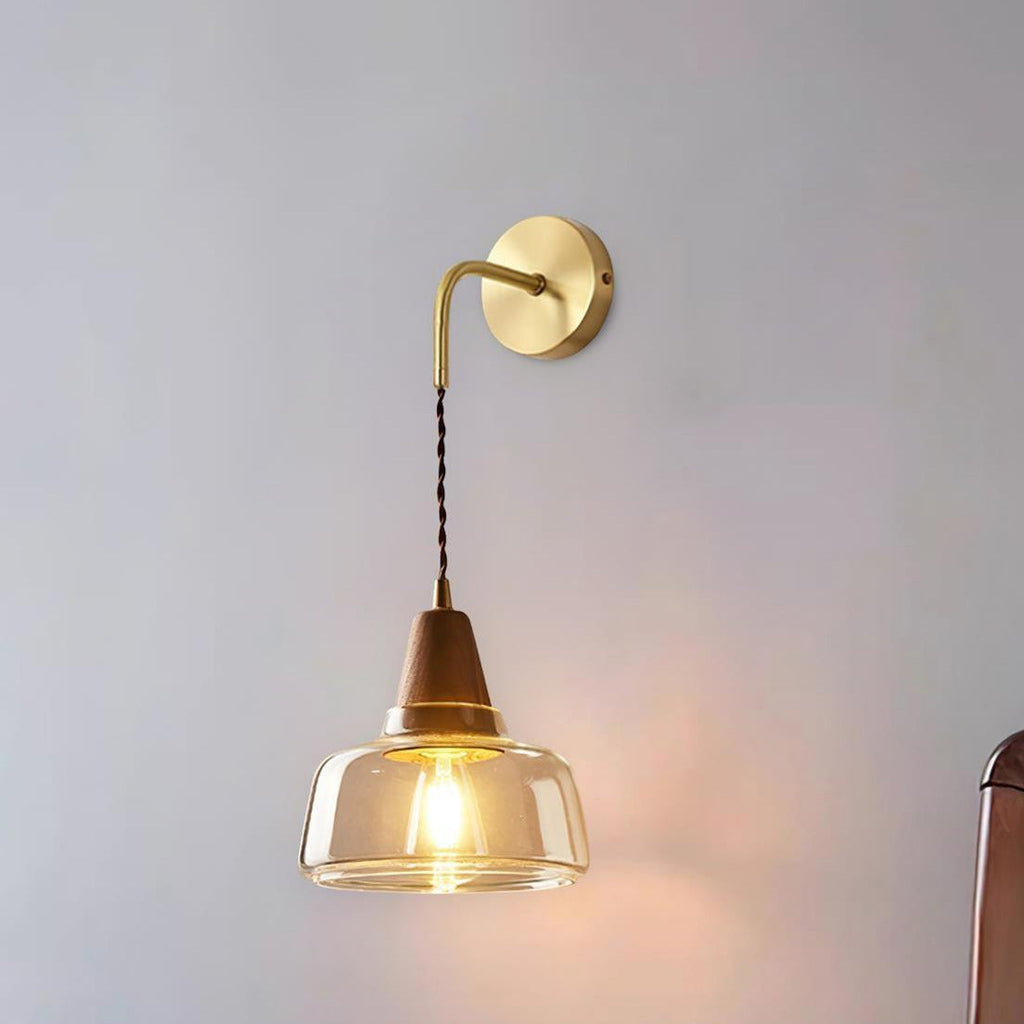 Clérachic bell glass wall sconce photographed alone on a plain gray background, its bulb glowing beneath the glass.