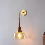 Clérachic bell glass wall sconce photographed alone on a plain gray background, its bulb glowing beneath the glass.